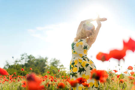 Blonde girl in a black bodysuit with a white hat walks in a rapeseed field, having fun, view from the backの写真素材
