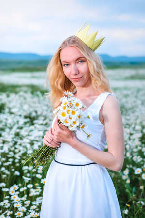 Blonde girl in a black bodysuit with a white hat walks in a rapeseed field, having fun, view from the backの写真素材