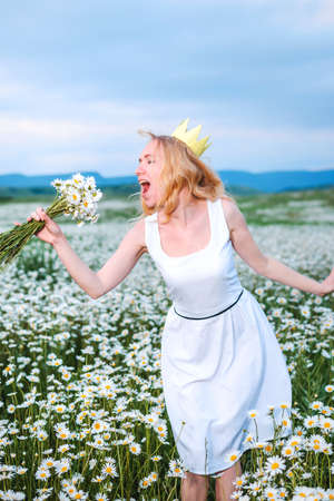 Girl in a hat and dress with a bouquet of poppies in a poppy fieldの写真素材