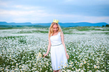 Girl in a hat and dress with a bouquet of poppies in a poppy fieldの写真素材
