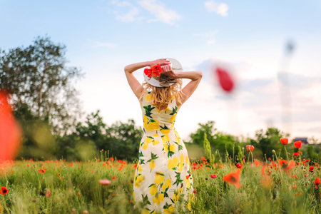 Girl in a hat and white dress with a bouquet of white wild daisies in a chamomile field