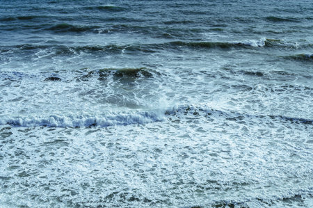 Foam waves on the sea during a storm in windy weather on a sunny day, beautiful sea backgroundの写真素材