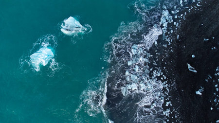 Pure Blue Glacier Ice on Black Sand Beach. Turquoise Sea Water. Icebergs at Diamond Beach in Iceland