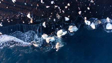 Pure Blue Glacier Ice on Black Sand Beach. Turquoise Sea Water. Icebergs at Diamond Beach in Icelandの写真素材
