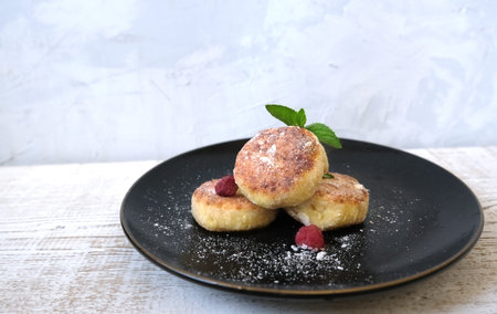 Ð¡heese pancake on the black plate on the wood background