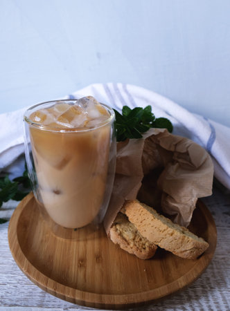 Iced coffee in thermo glass cup with cantuccini on the wood table