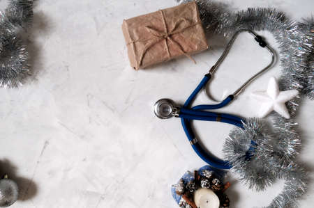 Christmas flatly. Concept of celebrating christmas and new year in the healthcare industry. Top view. Stethoscope with present box on a white background.の写真素材