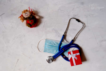 Christmas flatlay. Concept of celebrating christmas and new year in the healthcare industry. Top view. Blue stethoscope and red angel on a white background.の写真素材