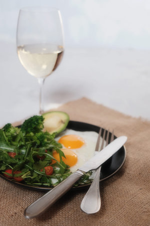 Keto food concept. Fried eggs with avocado, broccoli and salad arugula with tomato cherries. Place...