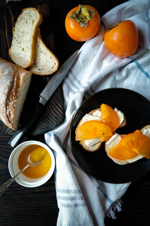 Gourmet bruschettas with camembert cheese or brie cheese, and honey, and persimmon on a wooden...