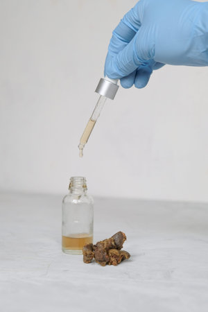 Medicine bottle with dropper and propolis with hand in protective glove isolated on the white...