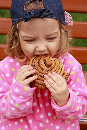 The little girl bites off a tasty loaf of breadの写真素材