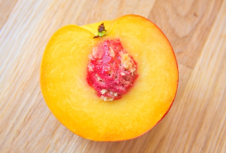 Half a peach isolated on wooden tableの写真素材