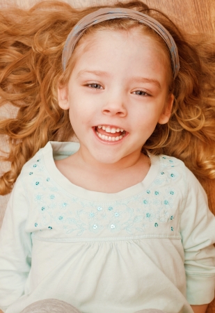 Happy little girl lying on floorの写真素材