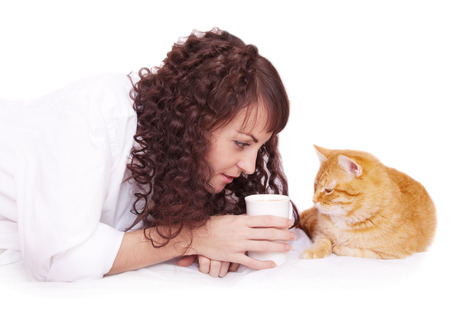 Girl with a cup of coffee and a cat in bedの写真素材