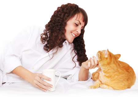 Girl with a cup of coffee and a cat in bedの写真素材