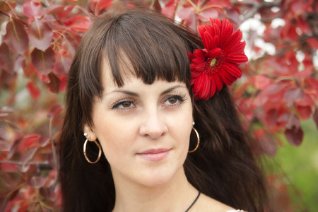 Portrait of a beautiful brunette on a background of red leavesの写真素材