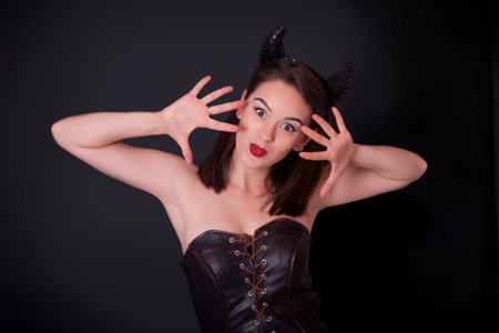 Smiling girl with small horns on a black background