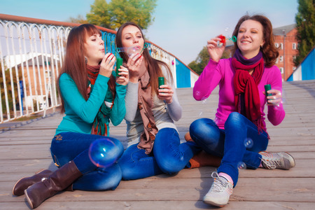 Three young beautiful women blow bubblesの写真素材