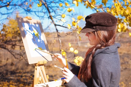 Girl with palette in hand sketches on white paperの写真素材