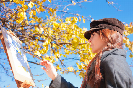 Girl with palette in hand sketches on white paperの写真素材
