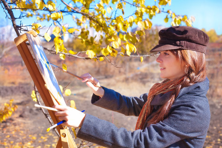 Girl with palette in hand sketches on white paperの写真素材
