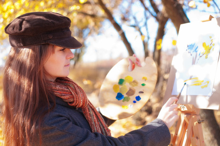 Girl with palette in hand sketches on white paperの写真素材