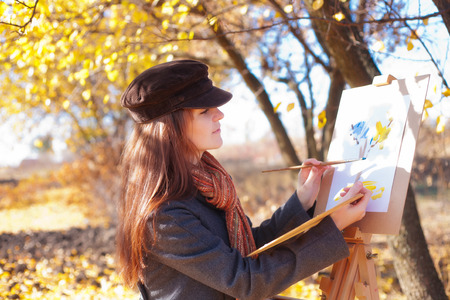The girl is engaged in painting on natureの写真素材