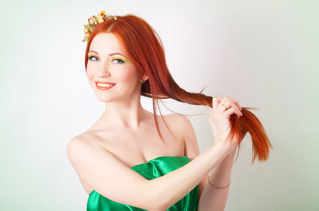 Portrait of beautiful red-haired girl with flowers in her hair and bright makeupの写真素材