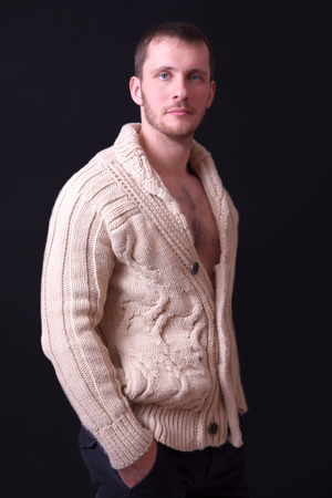 Portrait of a beautiful young man in a sweater, black backgroundの写真素材