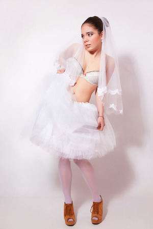 Bride in a skirt, underwear and veil on gray backgroundの写真素材