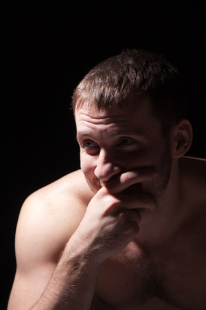 Image of shirtless man keeping his hand by face, black backgroundの写真素材