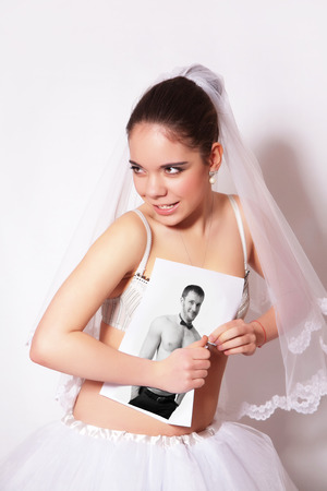 Bride broke the photo which shows the groom, gray backgroundの写真素材