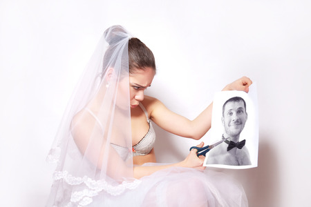 Bride scissor the photo which shows the groom, gray backgroundの写真素材