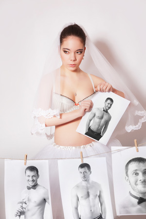 Bride broke the photo which shows the groom, gray backgroundの写真素材