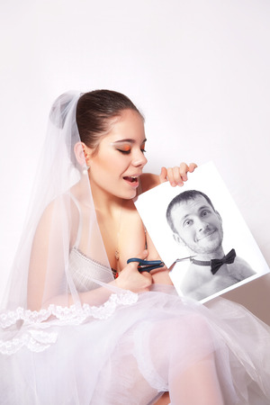 Bride scissor the photo which shows the groom, gray backgroundの写真素材