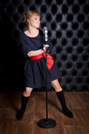 A beautiful girl with a microphone on stage singing a songの写真素材
