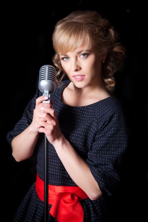A beautiful girl with a microphone on stage singing a songの写真素材