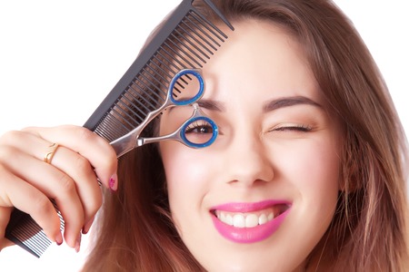 Cute girl hairdresser with scissors and comb closeup, isolated on whiteの写真素材