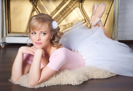 Beautiful ballerina with flower in her hair lying on the floorの写真素材