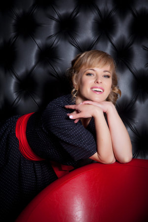 Girl in black dress standing near the chair, studio shotの写真素材