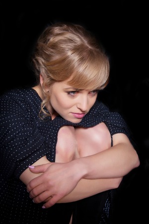 Portrait of sad pensive woman on a black backgroundの写真素材