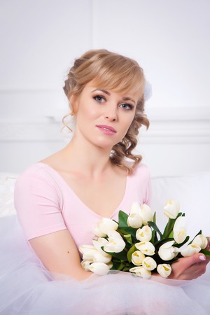 Portrait of a beautiful blonde woman with a bouquet of tulipsの写真素材
