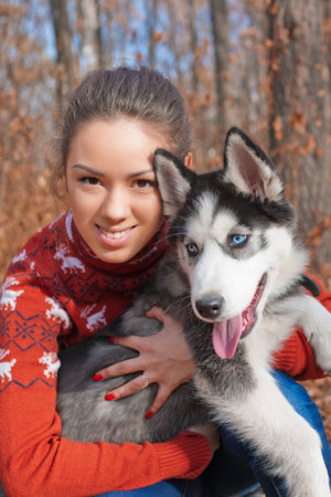 Beautiful young woman hugging huskies puppy for a walk in the park in autumn