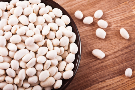 White beans in a brown plate on a wooden table, top viewの写真素材