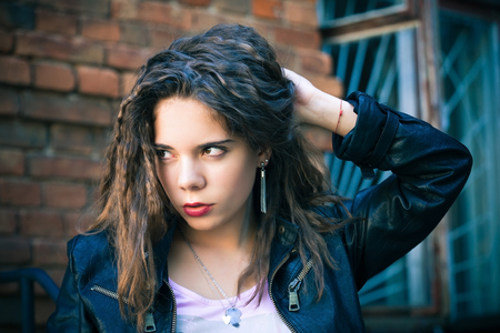 Young woman in leather jacket on a background of an old wallの写真素材