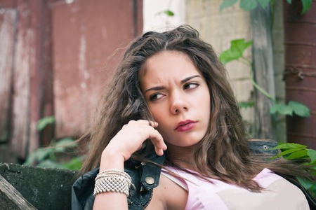 Young woman in leather jacket on a background of an old wallの写真素材