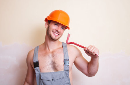 A man in overalls and helmet with a tool for dismantling