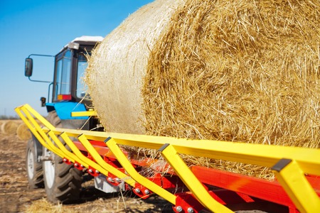 Straw on a trailer from a tractor in a field on a sunny dayの写真素材