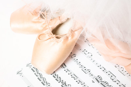 Ballet shoes, skirt and music sheet on a white background